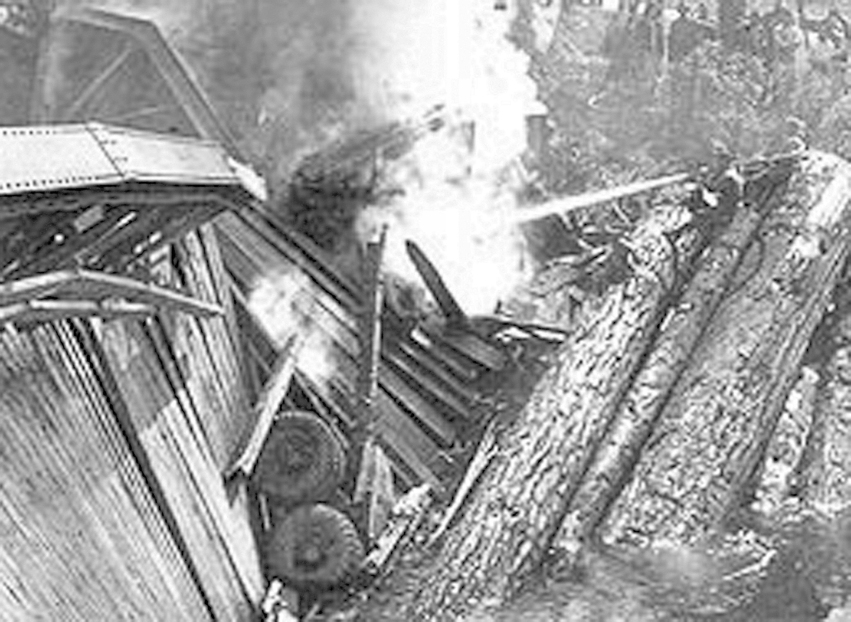 The wrecked log truck of F.H. Jarnagin lies smouldering amid the rubble of a steel-truss bridge over the Hoko River 4 miles west of Sekiu after the span collapsed beneath the overweight truck in 1947.  -- Photo from HistoryLink.org