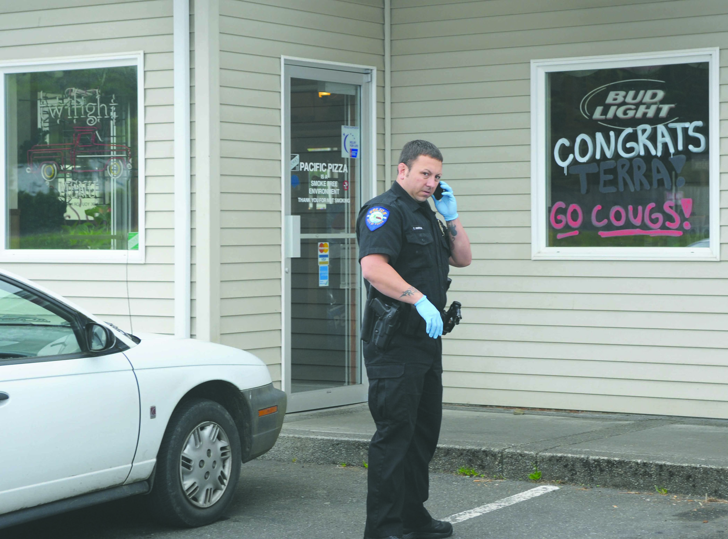 Forks Police Officer Todd Garcia is shown outside Pacific Pizza during Monday’s investigation.  -- Photo by Lonnie Archibald/for Peninsula Daily News