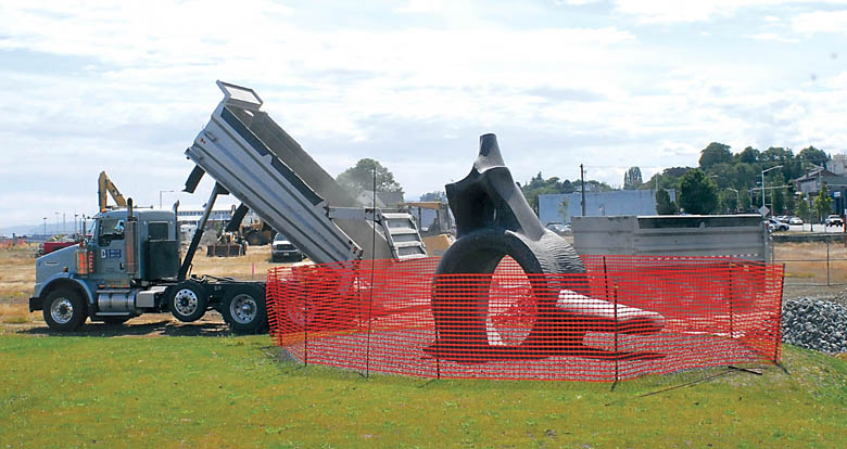 A dump truck unloads rock and gravel near the whale bone sculpture next to Valley Creek Estuary Park on Thursday as construction begins on West End Park along the Port Angeles waterfront. Keith Thorpe/Peninsula Daily News