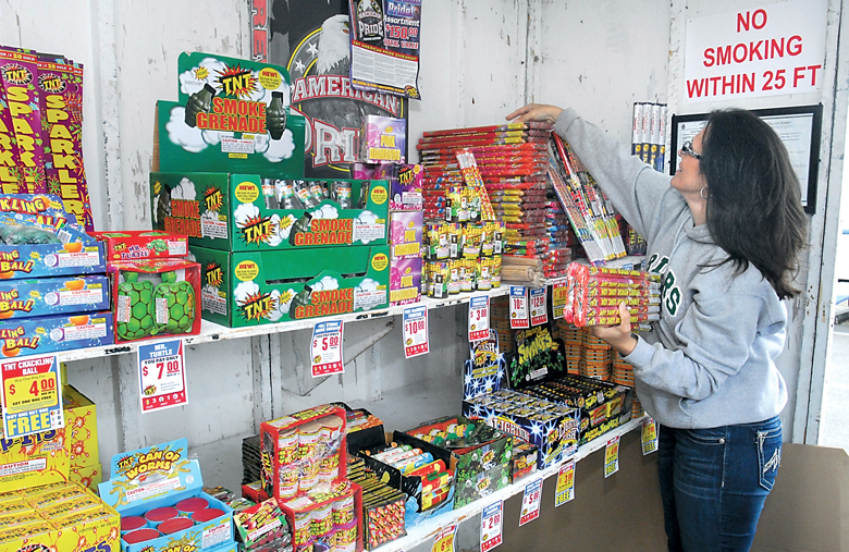 Michelle Weber stocks shelves with fireworks Friday at a stand operated by the Port Angeles High School Football Booster Club in the parking lot of Swain's General Store in Port Angeles. Keith Thorpe/Peninsula Daily News