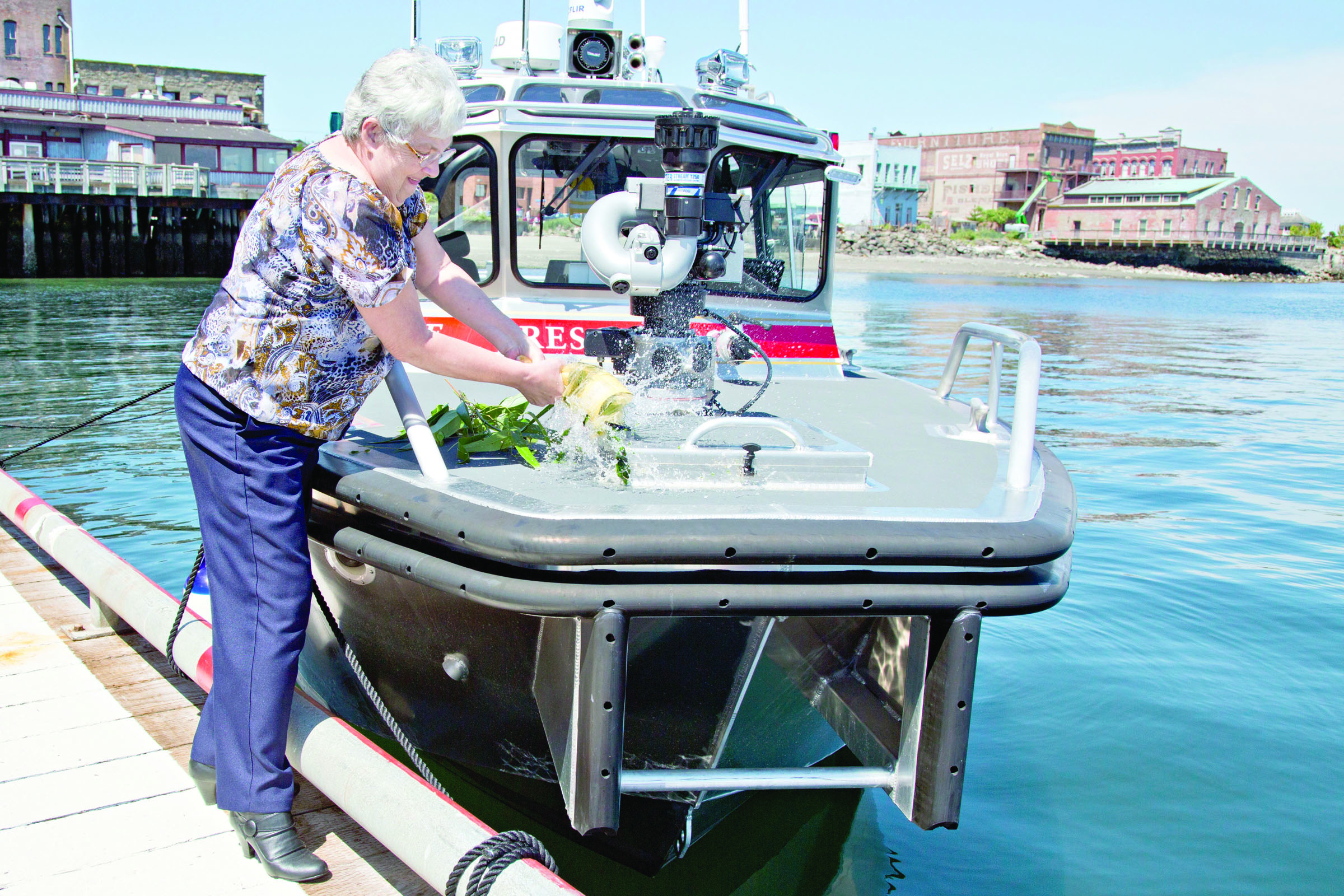 Retiring East Jefferson Fire Rescue secretary Lonibeth Harbison christens the new firefighting boat Guardian on Wednesday afternoon. — Crystal Craig/East Jefferson Fire Rescue