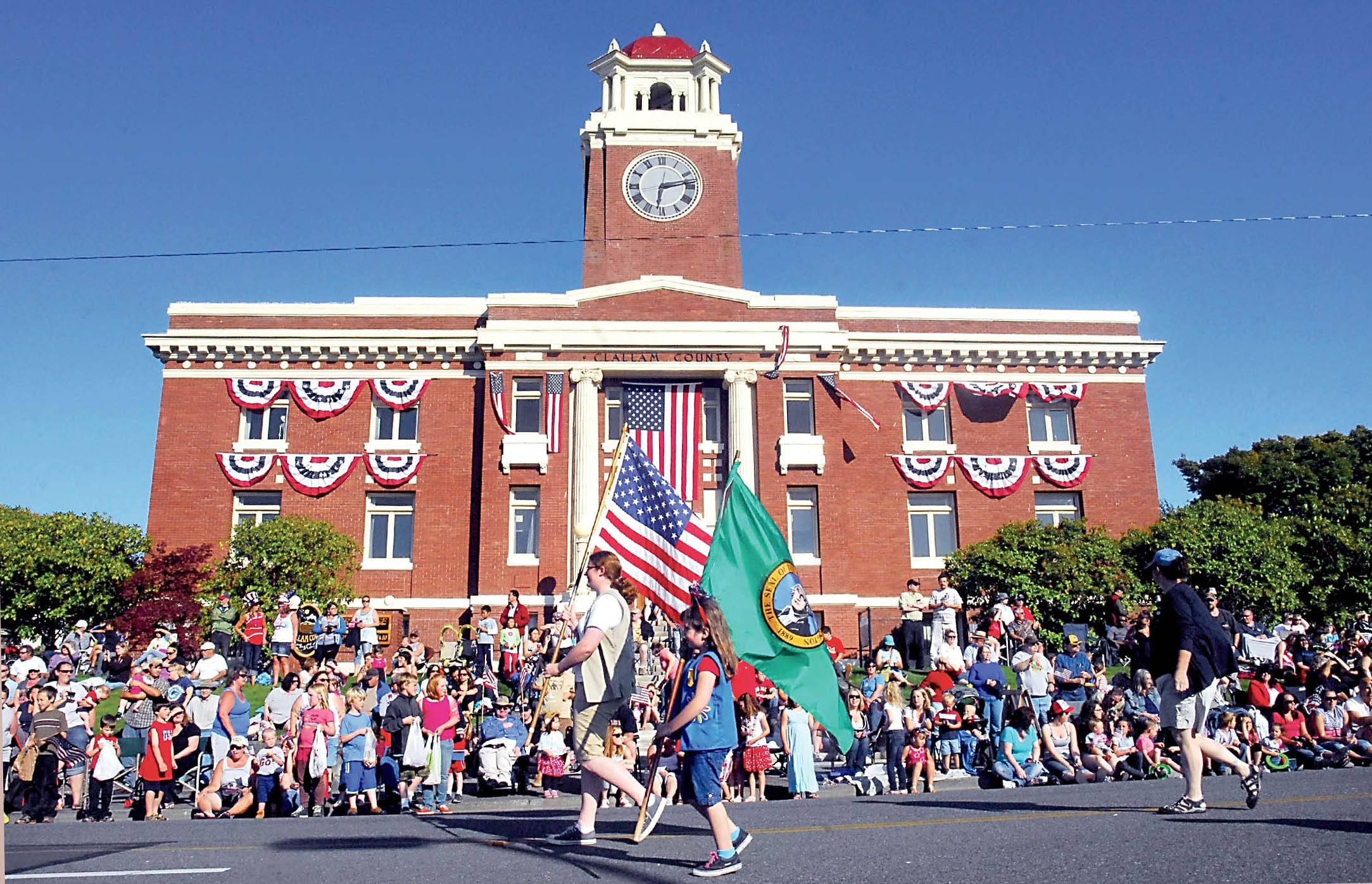 The Clallam County Courthouse is adorned with patriotic bunting as a girl scout color guard marches past it during the 2013 Independence Day parade in Port Angeles. —Photo by Keith Thorpe/Peninsula Daily News