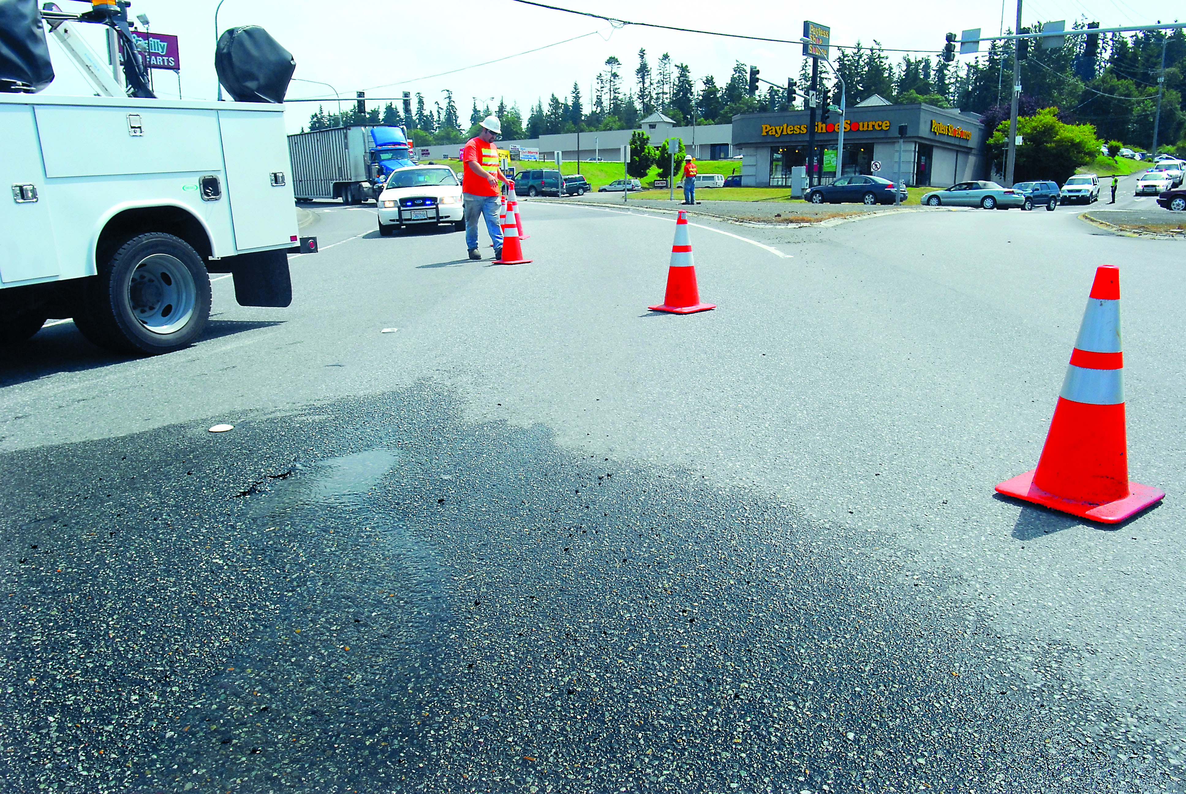 Port Angeles Public Works Department employee Cody Romero places traffic cones around the spot where an apparent water main break buckled the pavement and began leaking water in one of the westbound lanes of Front Street at Golf Course Road in Port Angeles on Tuesday afternoon. Authorities closed the lane to divert traffic around the break. Keith Thorpe/Peninsula Daily News