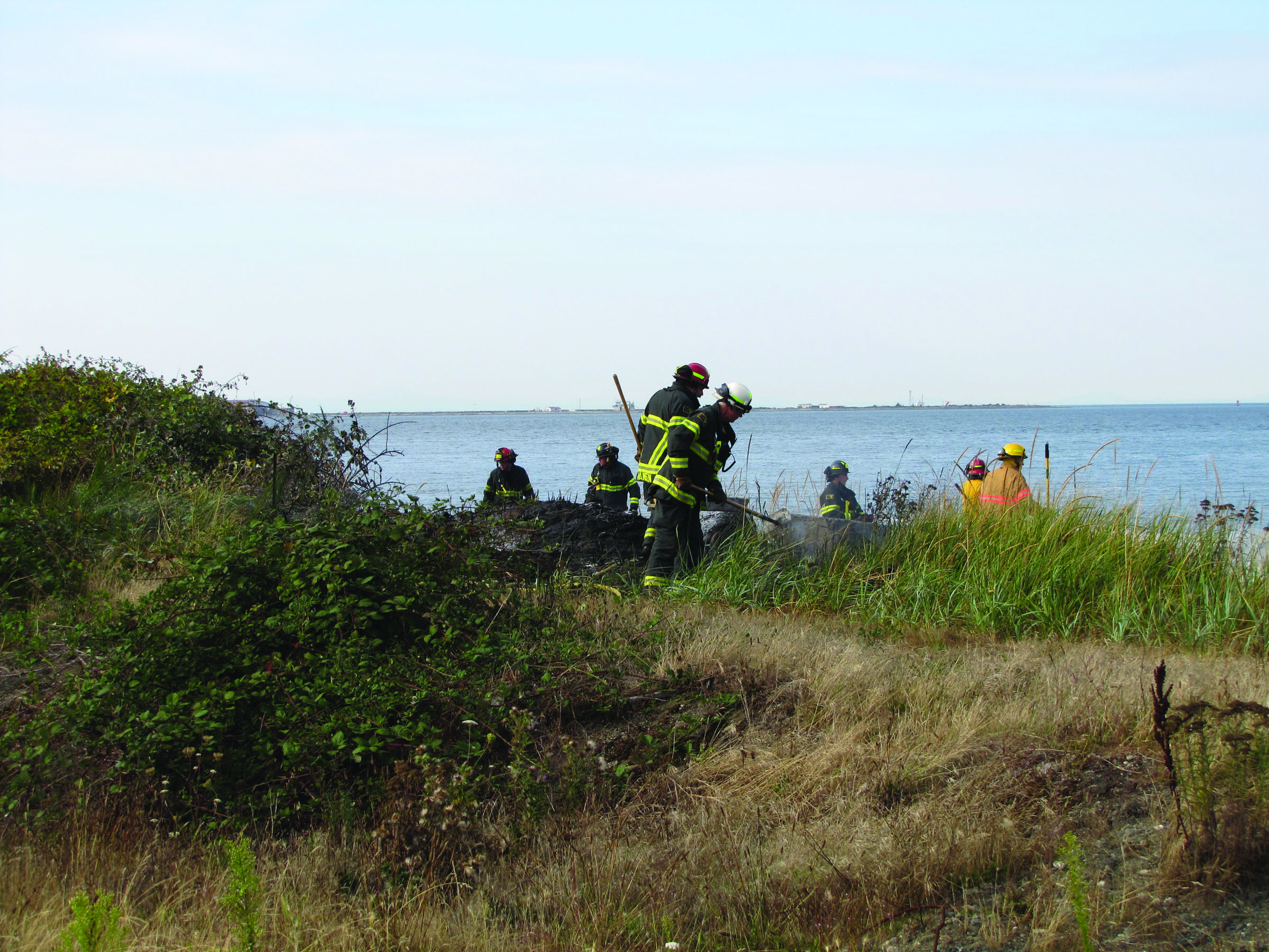 Port Angeles Fire Department and Clallam County Fire District No. 2 firefighters work to mop up a brush fire on the bluffs of the Rayonier Mill property just west of Ennis Creek in Port Angeles. Arwyn Rice/Peninsula Daily News