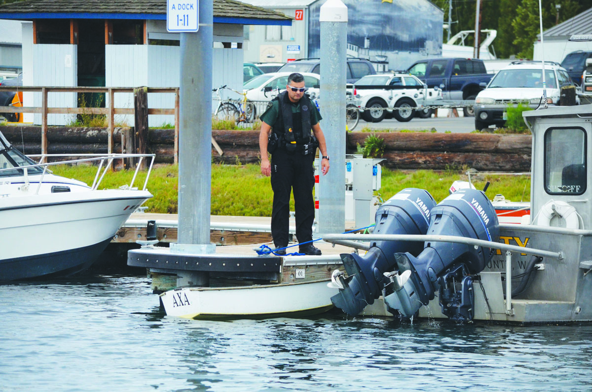 Jefferson County Sheriff's Deputy Gordon Tamura inspects the 6-foot skiff that was retrieved off Port Townsend on Monday. Charlie Bermant/Peninsula Daily News