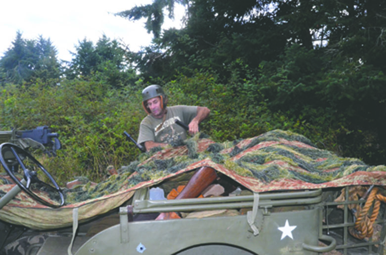 David King of Arlington arranges the camouflage on his Army jeep. Charlie Bermant/Peninsula Daily News