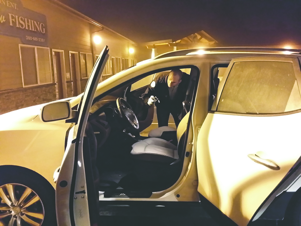 Clallam County Deputy Mark Millet looks into a white 2013 Hyundai Tucson found in a Sequim-area parking lot Friday after it was stolen from Port Angeles' Ruddell Auto Mall last Sunday. Clallam County Sheriff's Office