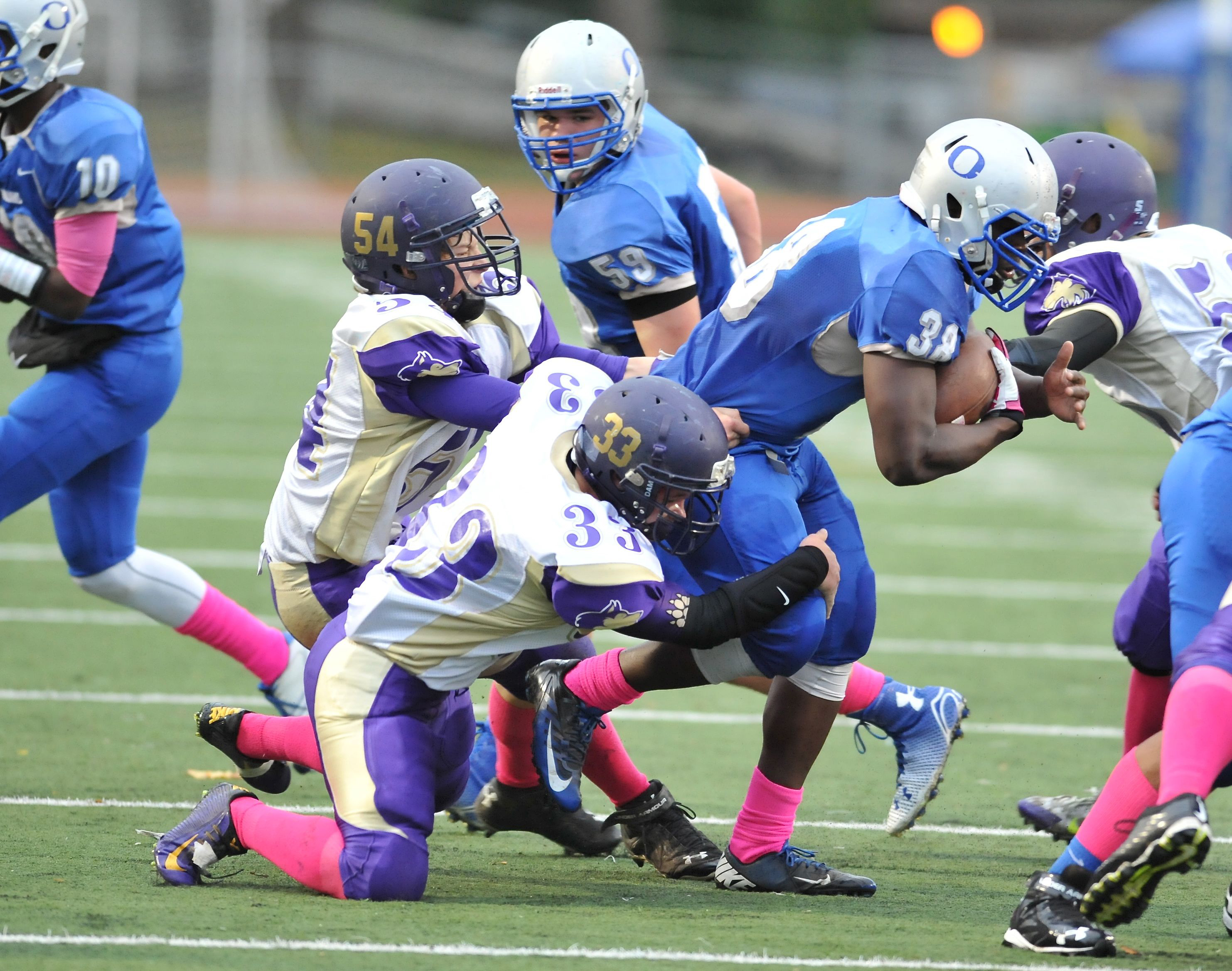 Sequim's Jack Ellison (54) and Brandon Stamper (33) team up to tackle Olympic fullback Geordyn Shinard last Friday. The Wolves will have one less day to prepare for this week's home game with Bremerton