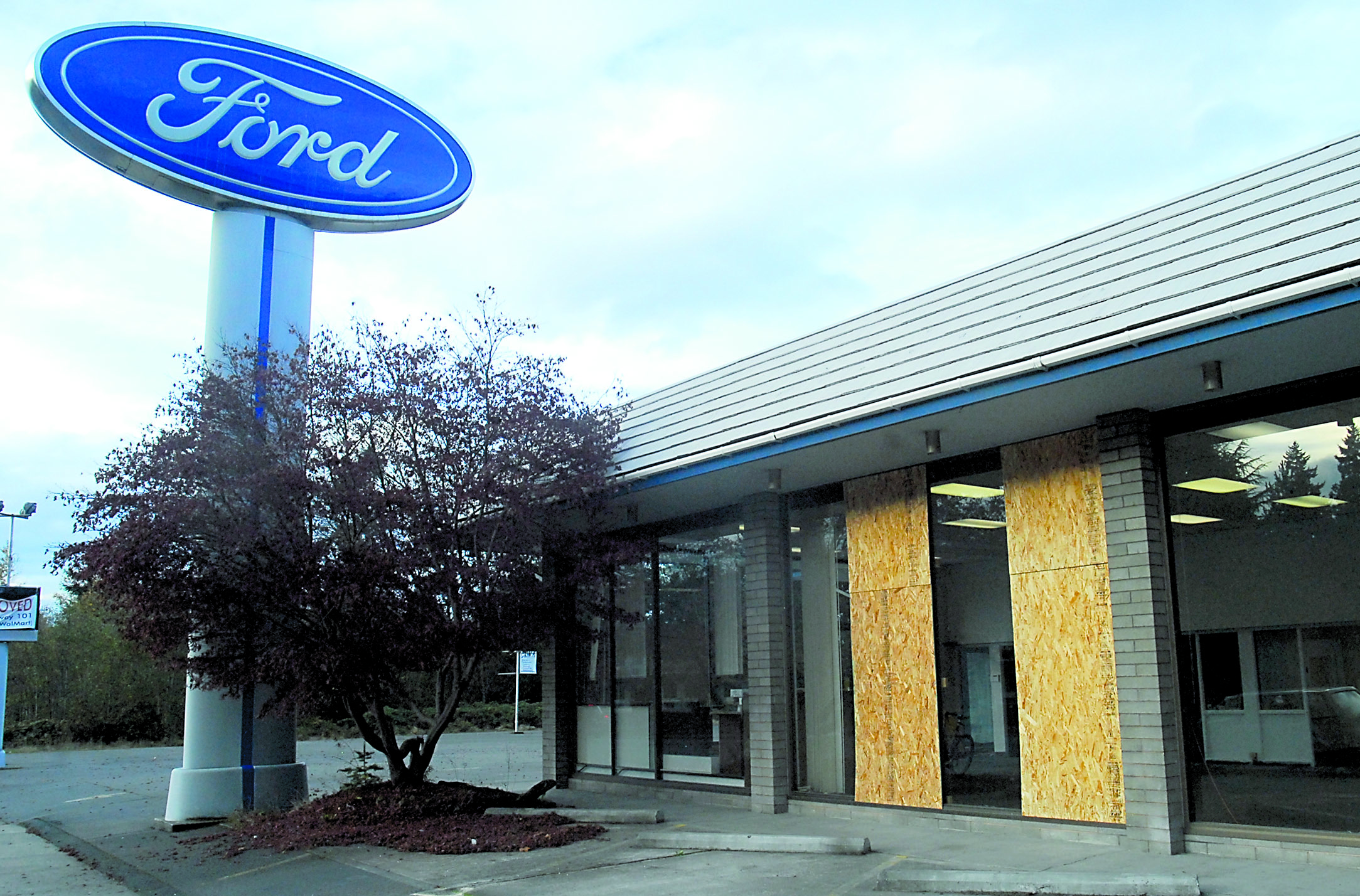 Plywood panels cover portions of the former Price Ford Lincoln showroom on East Front Street in Port Angeles after the windows were shot out midday Friday.  -- Photo by Keith Thorpe/Peninsula Daily News