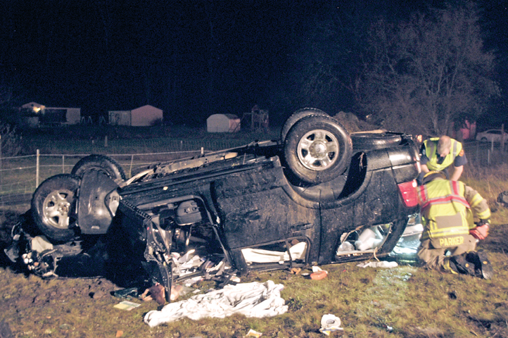 Firefighters look through the interior of an SUV that rolled over Thursday evening south of U.S. Highway 101 to the west of the River Road exit. Both adult occupants