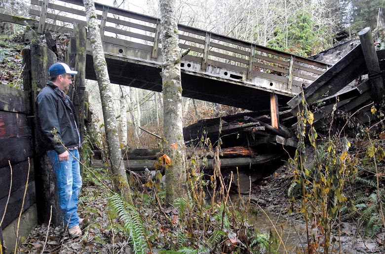 Shawn Gallacci looks at the shattered remains of the private bridge on Garling Road leading into his neighborhood east of Port Angeles on  Saturday. Keith Thorpe/Peninsula Daily News