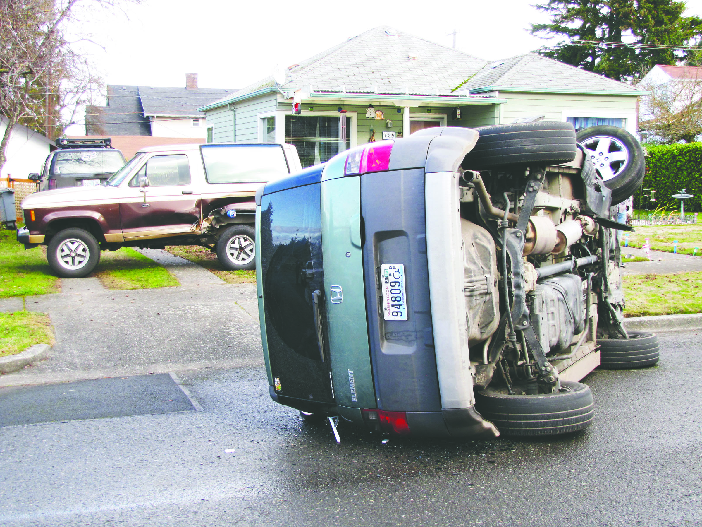 A Honda Element lays on its side near a damaged Chevy Blazer on East Third Street near Jones Street