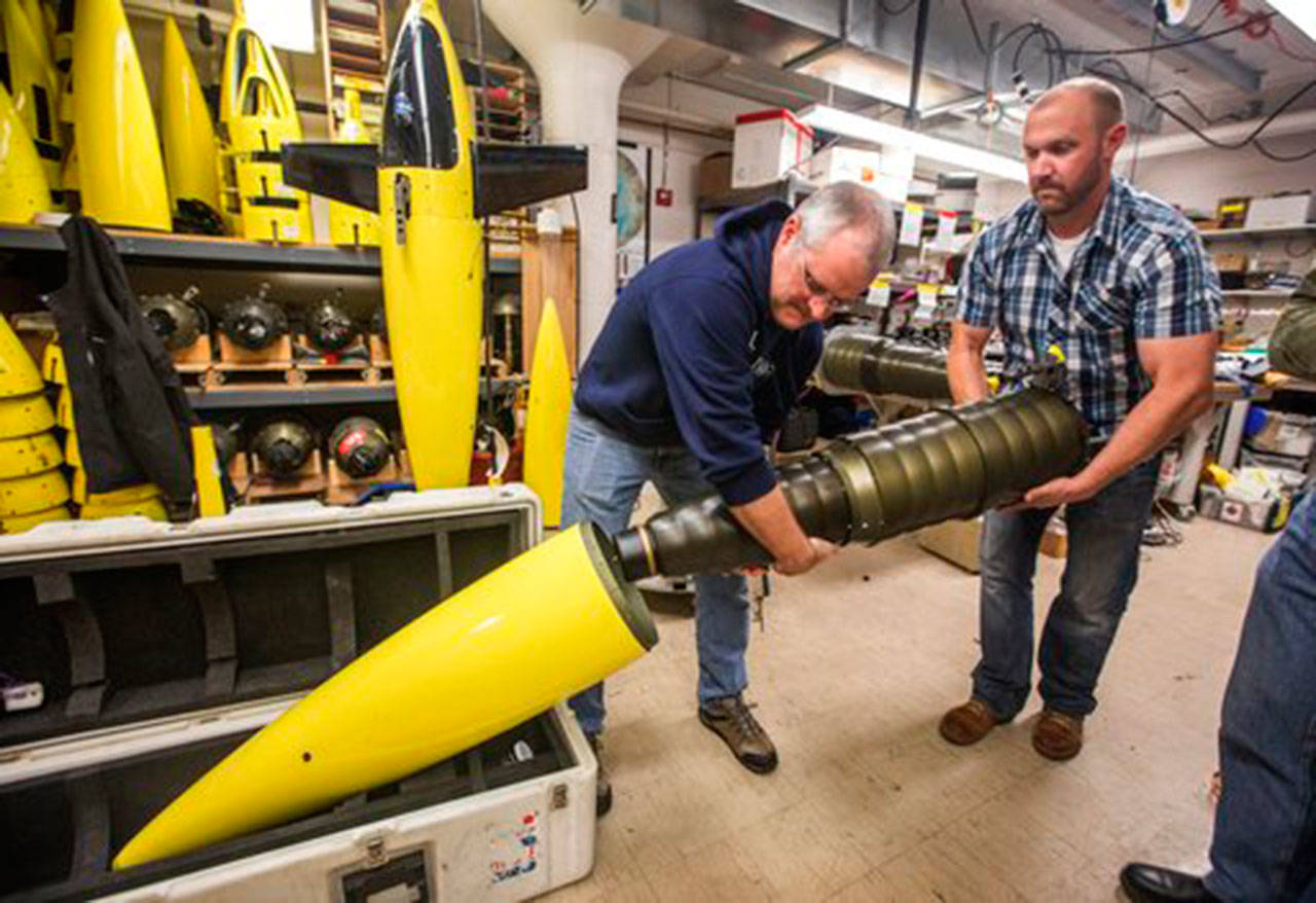 In a Nov. 20 photo, University of Washington oceanographers Jason Gobat and Ben Jokinen load the “pupa” into the underwater fairing “sea glider” that will be used in an antarctic expedition to gather data under the sea ice sheets to estimate future melting and sea level rise. (Steve Ringman/The Seattle Times via AP)