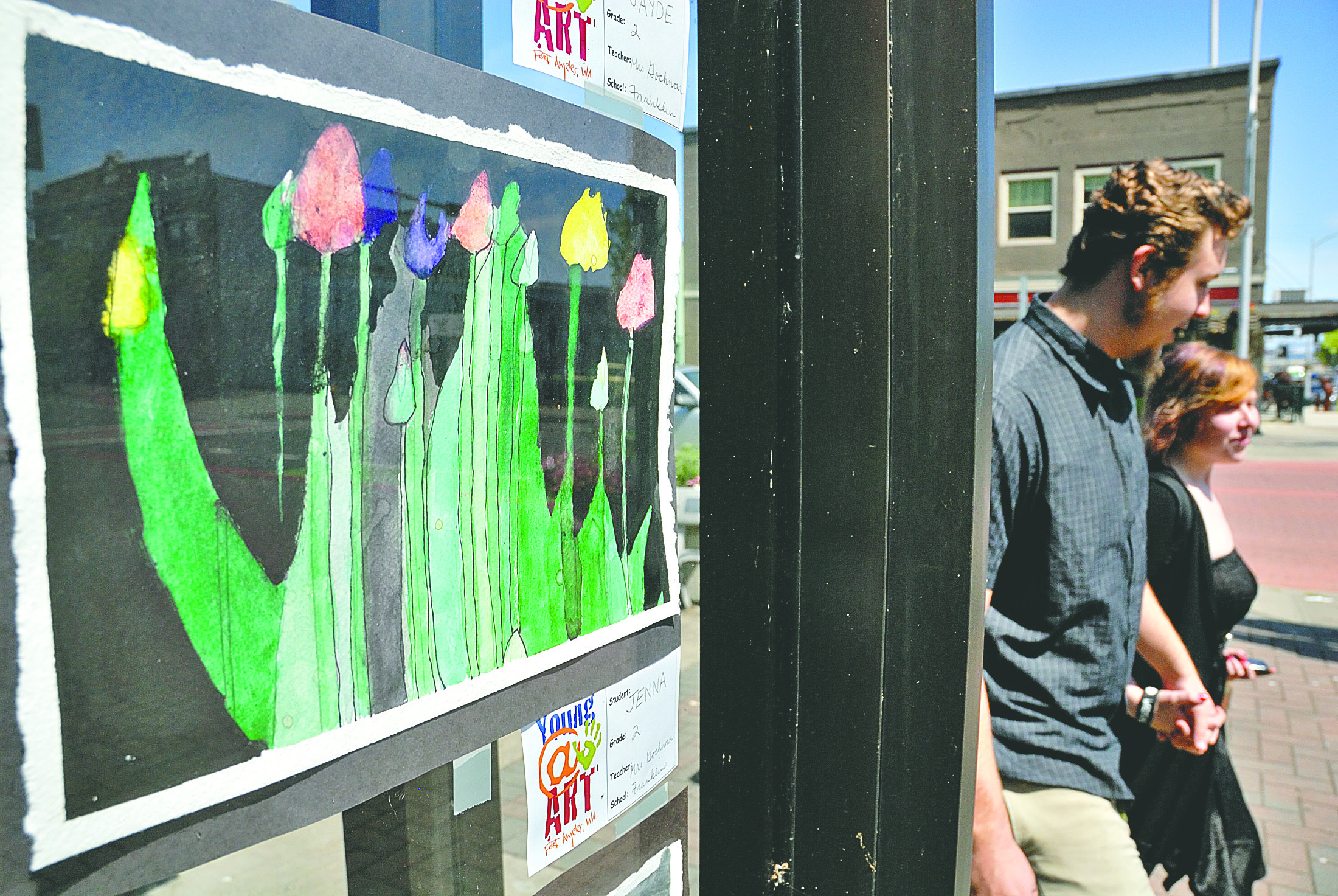 Flowery artwork created by a Franklin Elementary School second-grader named Jenna adorns a window at Maurices in Port Angeles as friends Cody Thompson and Amber Martin walk by Thursday. The artwork is part of the Young@Art project. Chris Tucker/Peninsula Daily News