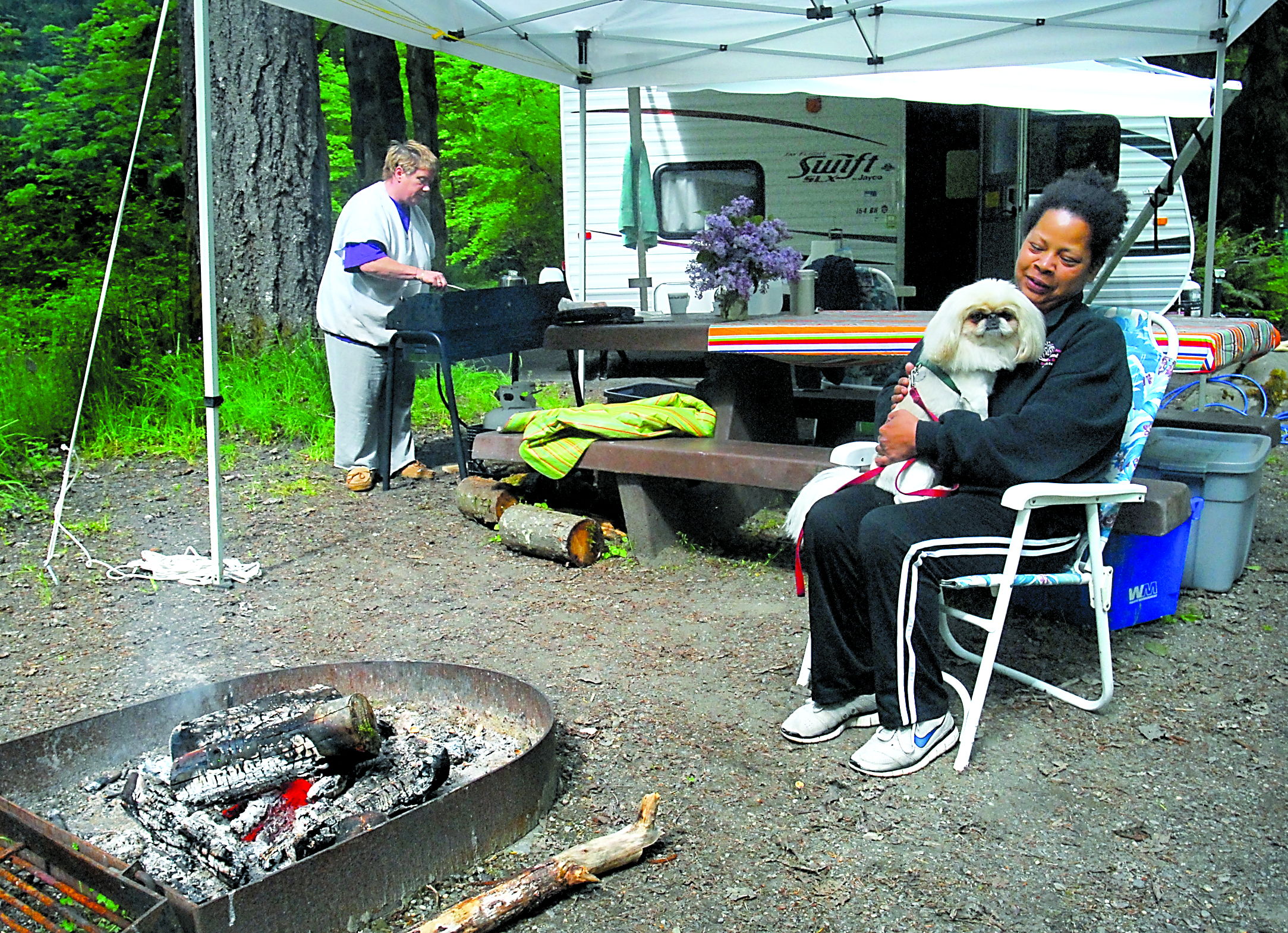 Tammie Hawkins sits by a campfire with dog