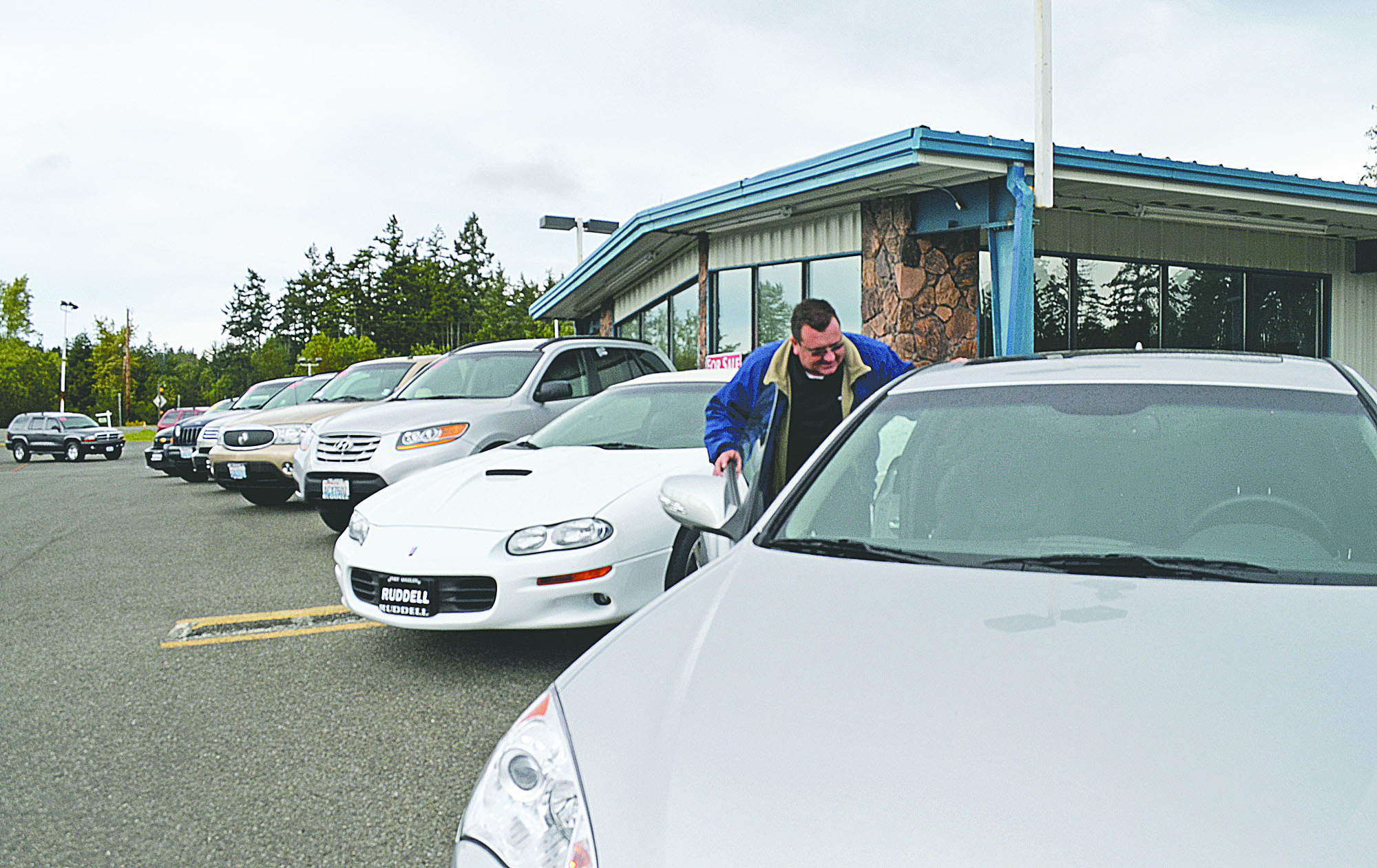 Salesman Rob White prepares some of the cars for a six-day auto sale that will take place at the old Ford dealership south of Port Townsend.  -- Photo by Charlie Bermant/Peninsula Daily News