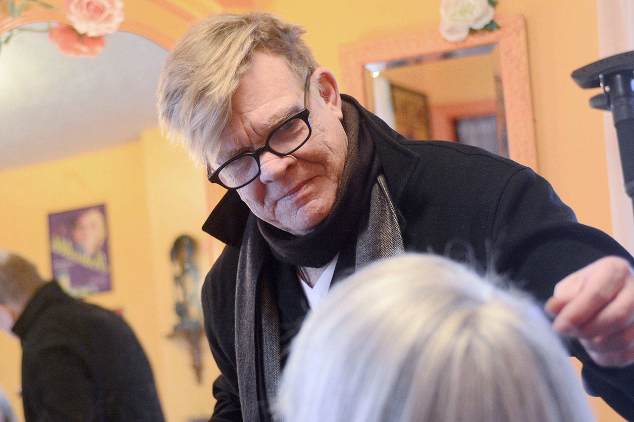 Michael Costain, who owns Wig Master Associates in Port Townsend, works with a client Thursday. (Jesse Major/Peninsula Daily News)