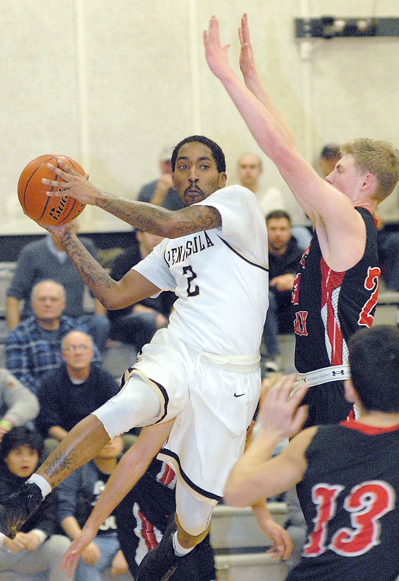 Peninsula’s Cameron Burton, left, takes to the air as Skagit Valley’s Nate Maudlin and Chris Walcott, lower right, defend the lane during the first half of the Pirates’ 82-80 loss.                                Keith Thorpe/Peninsula Daily News