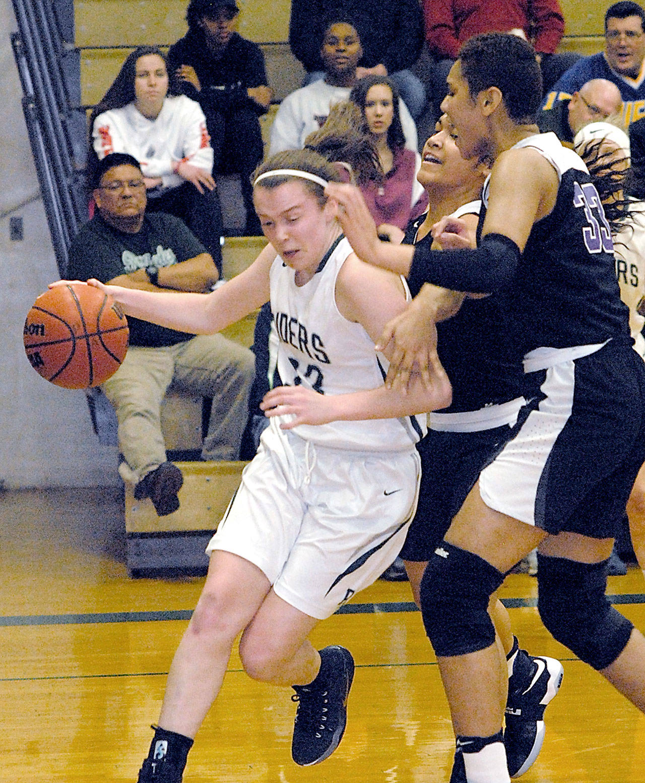 Port Angeles’ Jaida Wood, left drives along the baseline past Foster defenders Moeshana Maiava and Emolani Morris, right, in the second quarter of Friday night’s playoff game at Port Angeles High School.                                Keith Thorpe/Peninsula Daily News