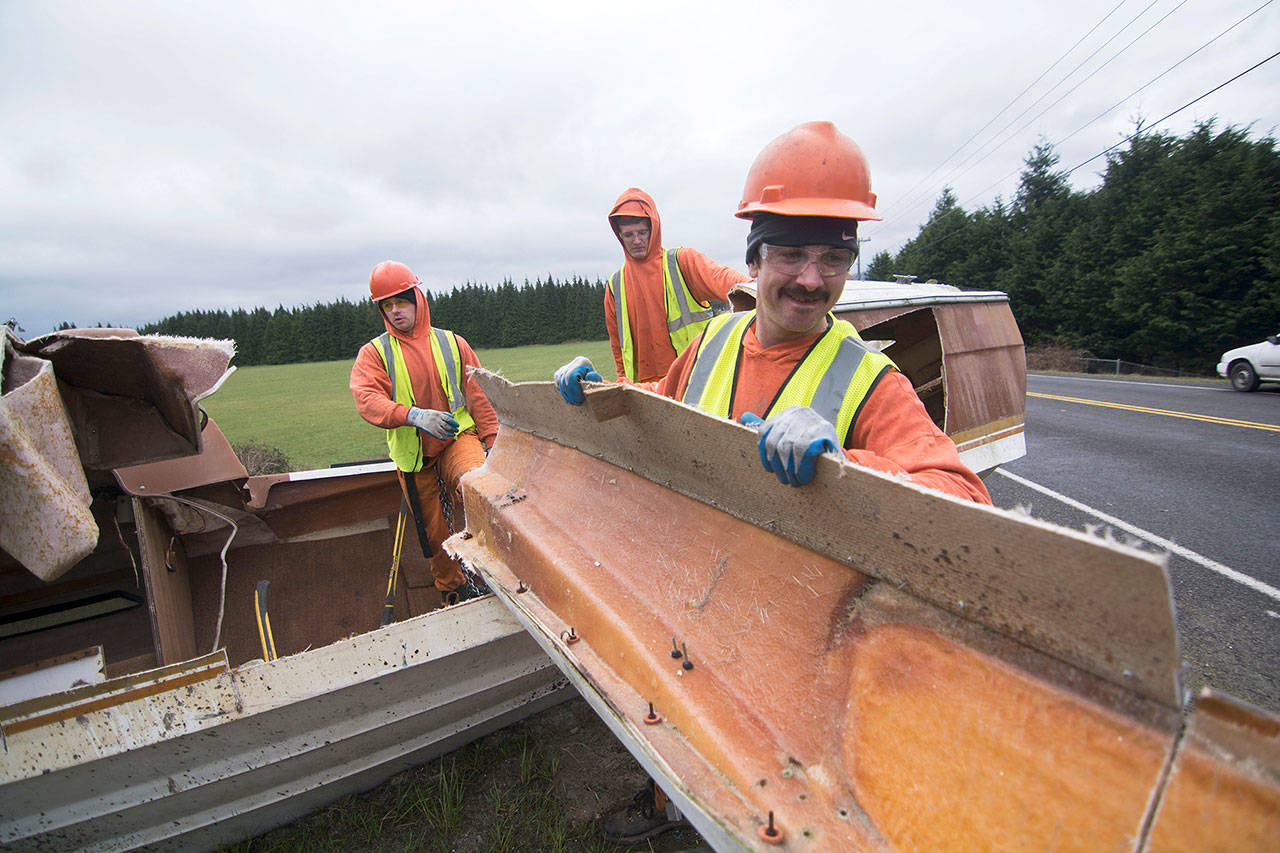 Clallam County jail inmate Jon Heilman carries a piece of an abandoned boat to the Clallam County Chain Gang’s trailer on Wednesday. (Jesse Major/Peninsula Daily News)