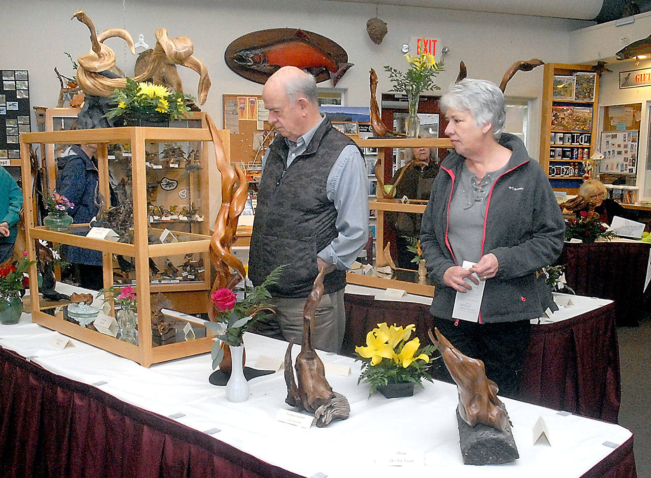 Mark Turley, left, and Jann Hale, both of Sequim, examine a table filled with driftwood sculptures at the Dungeness River Audubon Center at Sequim’s Railroad Bridge Park during last year’s Spring Diftwood Art Show. (Keith Thorpe/Peninsula Daily News)