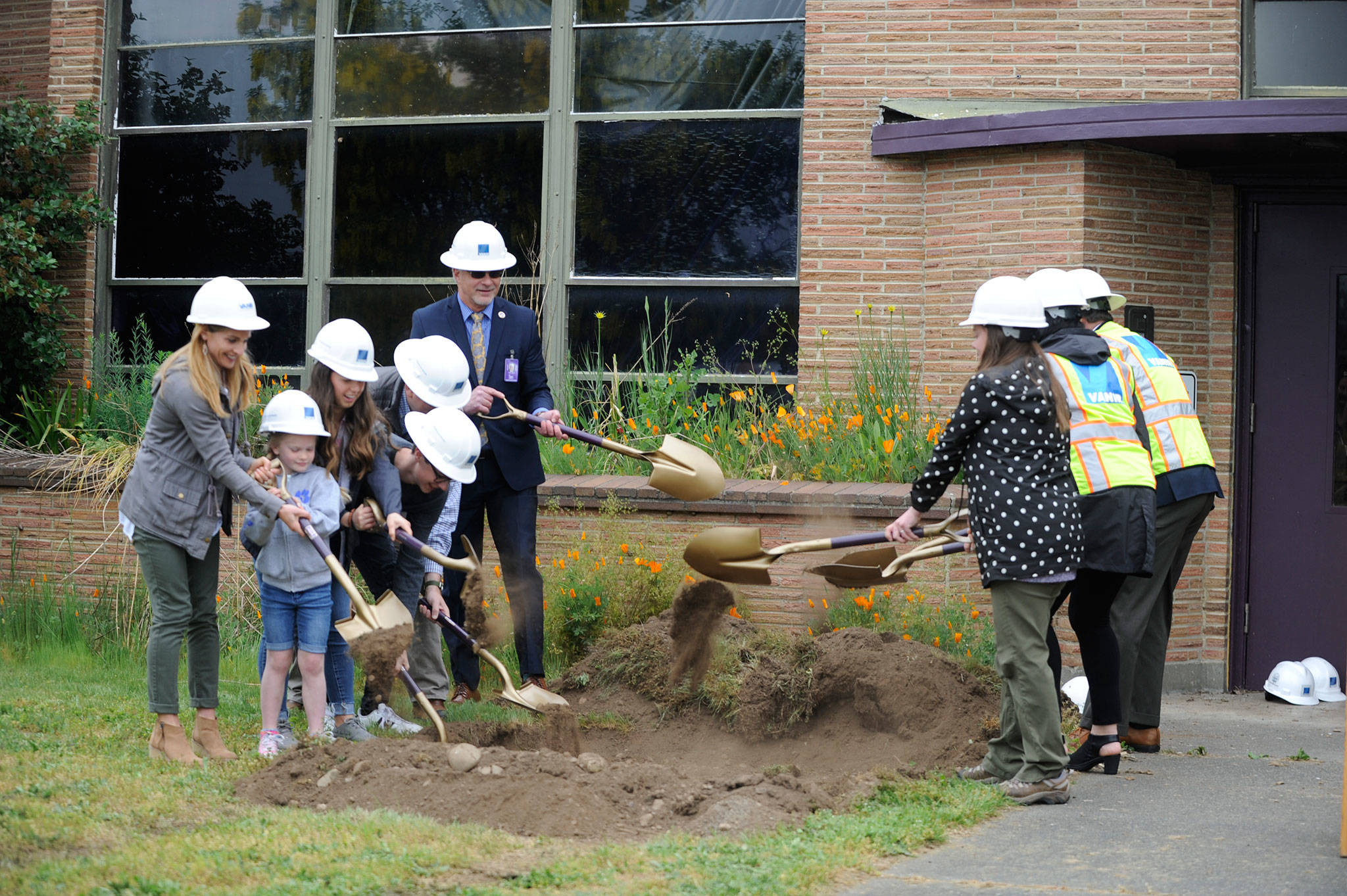 Sequim School District Board Director Robin Henrikson, left, with Helen Haller kindergartner Emma Bixby, student board representatives Tea Gauthun and Damon Little, board director Brian Kuh, Superintendent Gary Neal and board President Heather Short, right, with Vanir Construction Management Inc., project director Tobi Maggi and northwest area development manager Bernie O’Donnell, perform a groundbreaking ceremony at the Sequim Community School where a new central kitchen will be built in the northwest corner and the unused portions demolished. (Erin Hawkins/Olympic Peninsula News Group)