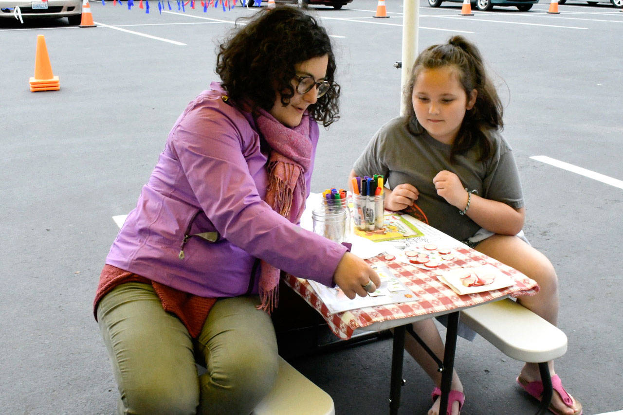 Stephanie Brooks, YMCA Jefferson County Snap-Ed coordinator, plays Veggie Bingo with 7-year-old Jaxzen Berg of Port Townsend at the new location of the Wednesday Farmers Market at the Haines Street Park and Ride Transit Center. (Jeannie McMacken/Peninsula Daily News)