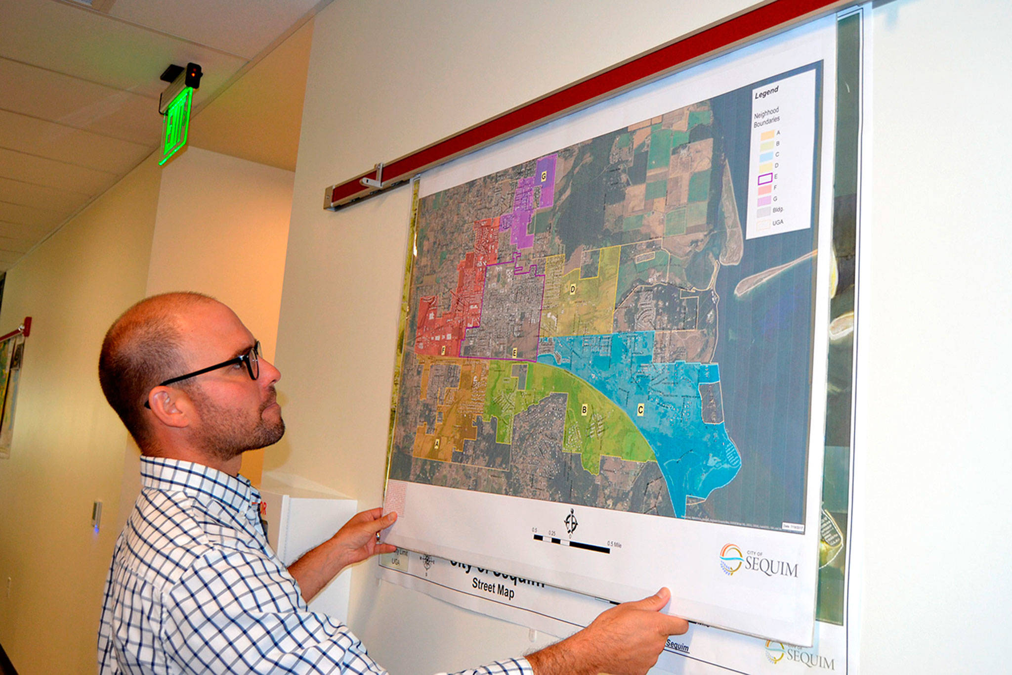 Sequim Assistant City Manager Joe Irvin holds maps of different regions in the city of Sequim in 2017 prior to a Neighborhood Visioning Meeting. Irvin plans to leave the city to work in Healdsburg, Calif. (Matthew Nash/Olympic Peninsula News Group)