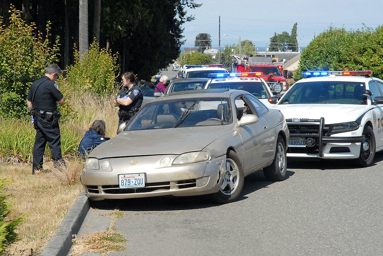 Port Angeles police stand next to a vehicle that was pulled over after it was allegedly spotted being driven erratically and sideswiping cars in near Jesse Webster Park on Friday. (Keith Thorpe /Peninsula Daily News)