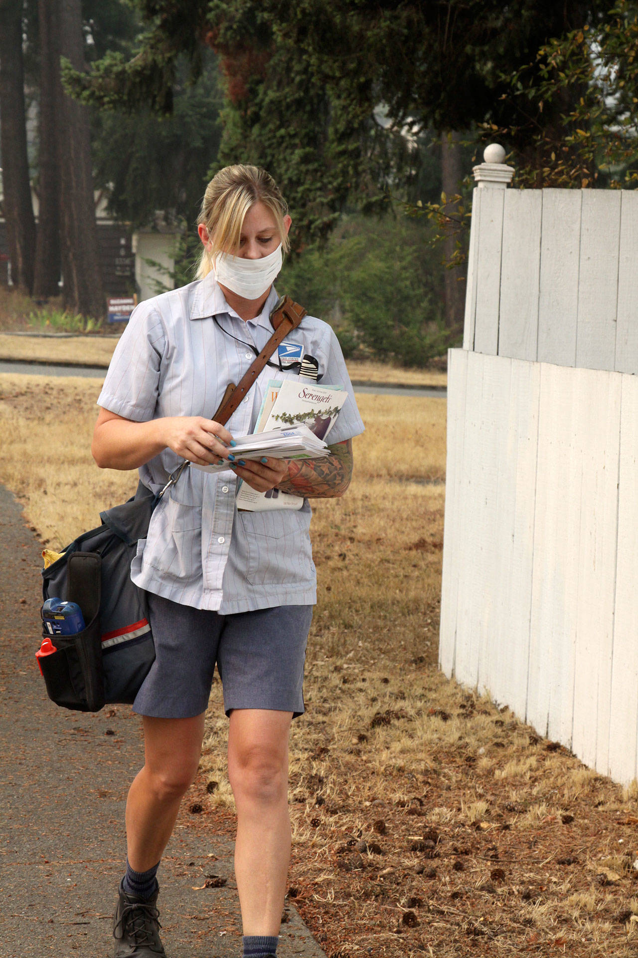 Jennifer Wendell of the United States Postal Service walks her rounds on South Ennis Street in Port Angeles on Monday morning with a for breathing amid the smoky air. (Dave Logan/for Peninsula Daily News)