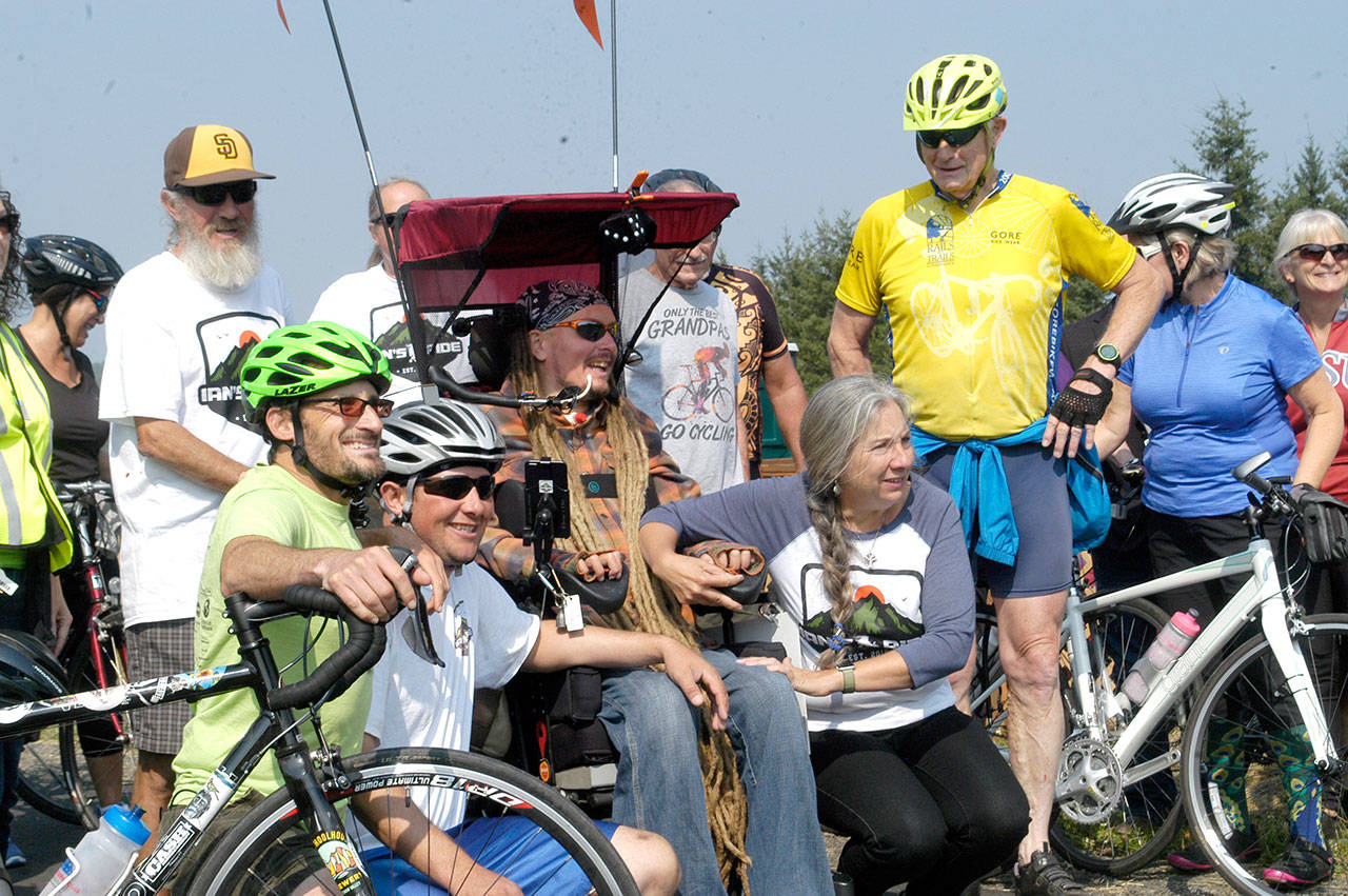 Ian Mackay and his supporters stop to celebrate after crossing the Clallam-Jefferson County line on the Olympic Discovery Trail at Diamond Point Road on Friday. Mackay had traveled on his wheelchair from Coeur d’Alene, Idaho to highlight the need for wheelchair-accessible trails in Washington. (Rob Ollikainen/Peninsula Daily News)