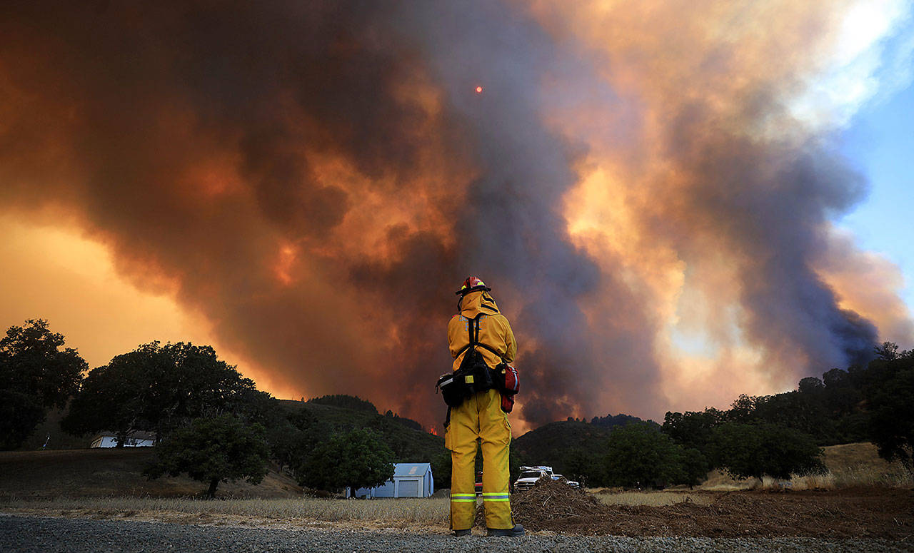 In this Aug. 2 file photo a tower of smoke pours from Cow Mountain as Burney, Calif., firefighter Bob May keeps a watch on surrounding vegetation for spot fires during the River wildfire near Lakeport, Calif. (Kent Porter/The Press Democrat via AP)