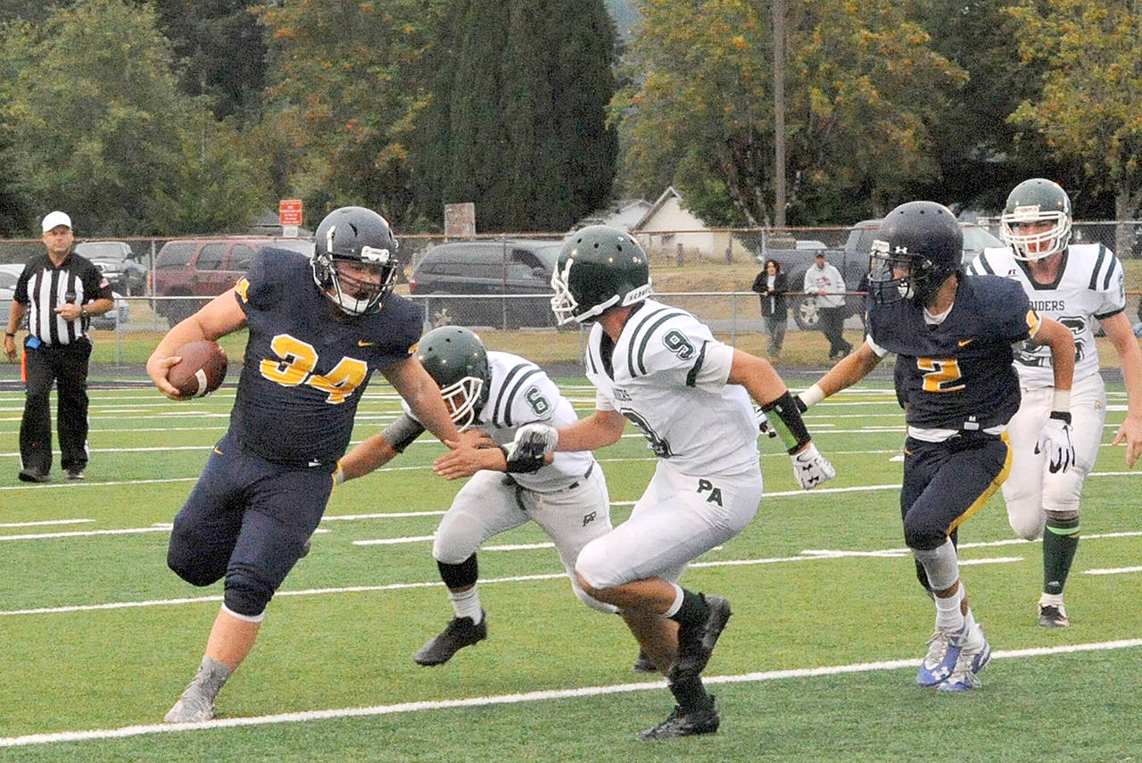 Lonnie Archibald/for Peninsula Daily News Forks’ Tristen Pisani, left, looks for yardage while Port Angeles’ Chris Guttormsen (6) and Cade Flanagan (9) defend.