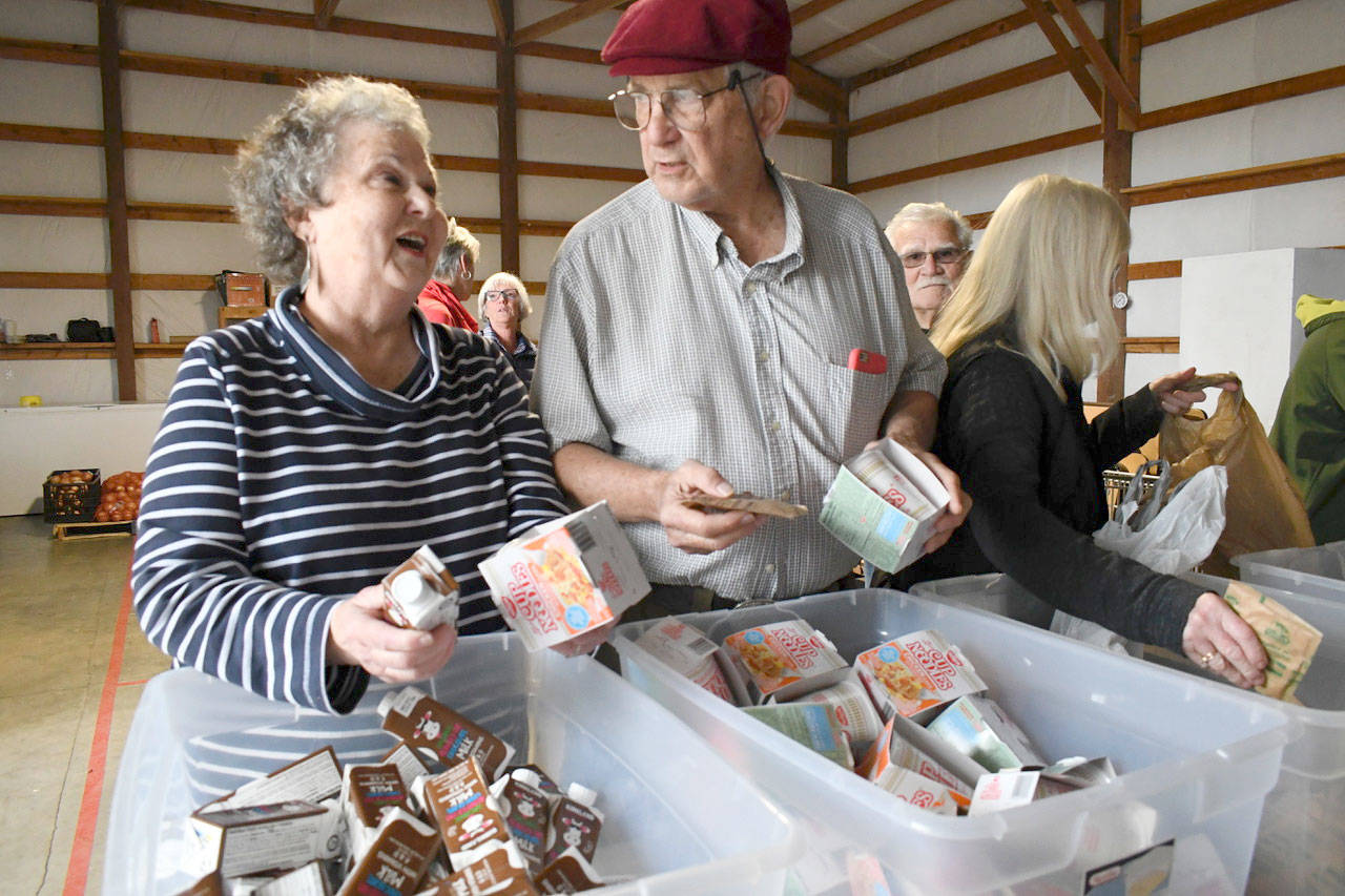 Volunteers Margie Gormley and Bob Cross, both from Port Ludlow, pack meals for Chimacum School students as part of the Chimacum Backpacks for Kids program. About two dozen community members committed to help out the non-profit Thursday mornings throughout the school year at the Tri-County Food Bank. (Jeannie McMacken/Peninsula Daily News)