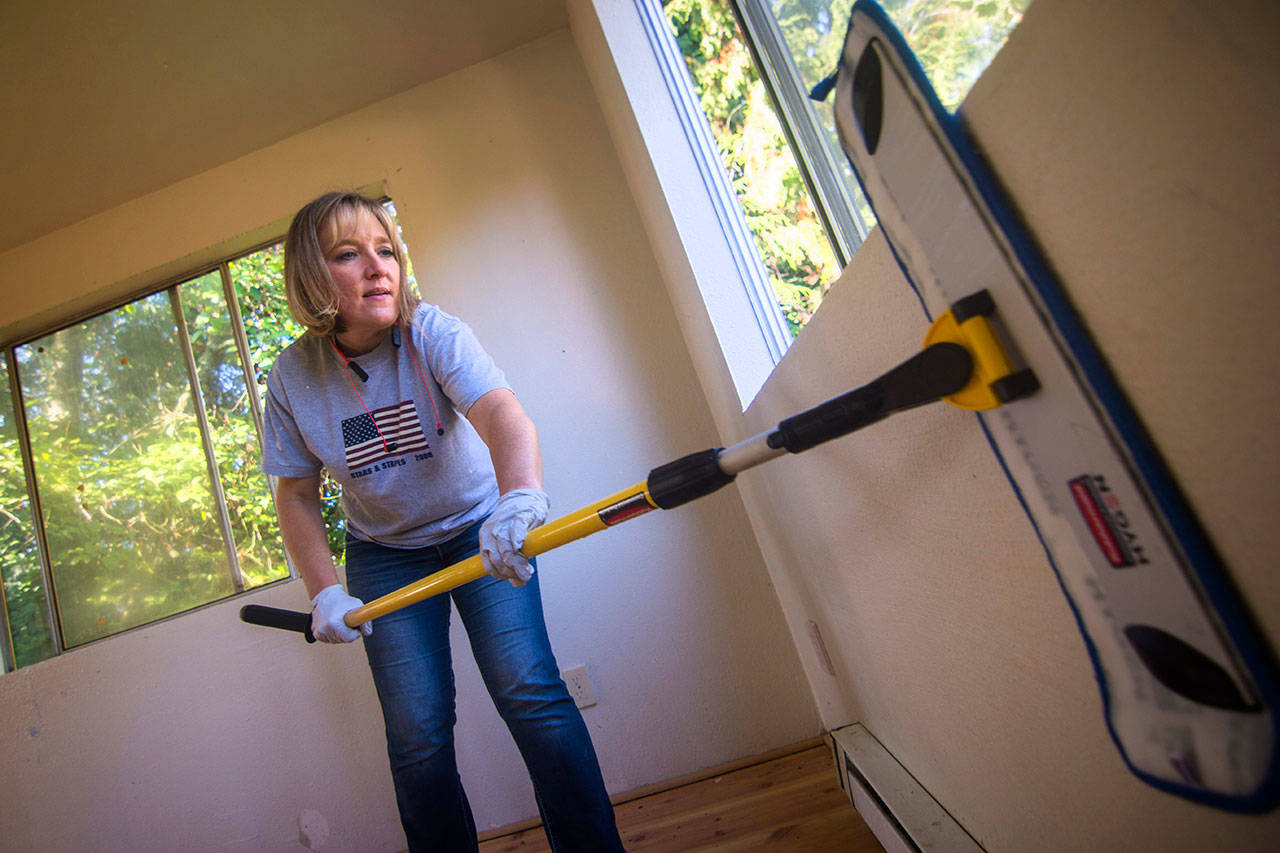 Kelly Sanders, an elementary school teacher, cleans the walls of a house she is preparing to turn into an Oxford House for recovering drug addicts. (Jesse Major/Peninsula Daily News)