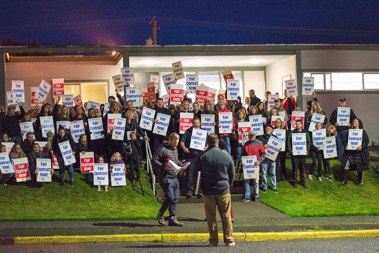 Paraeducators and their supporters hold signs outside the Port Angeles School District central services building. (Jesse Major/Peninsula Daily News)