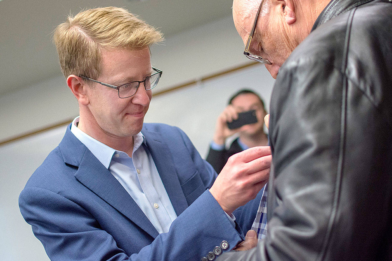 U.S. Rep. Derek Kilmer puts a pin on a veteran’s jacket during a pinning ceremony for Vietnam War era veterans in Port Ludlow Thursday evening. (Jesse Major/Peninsula Daily News)