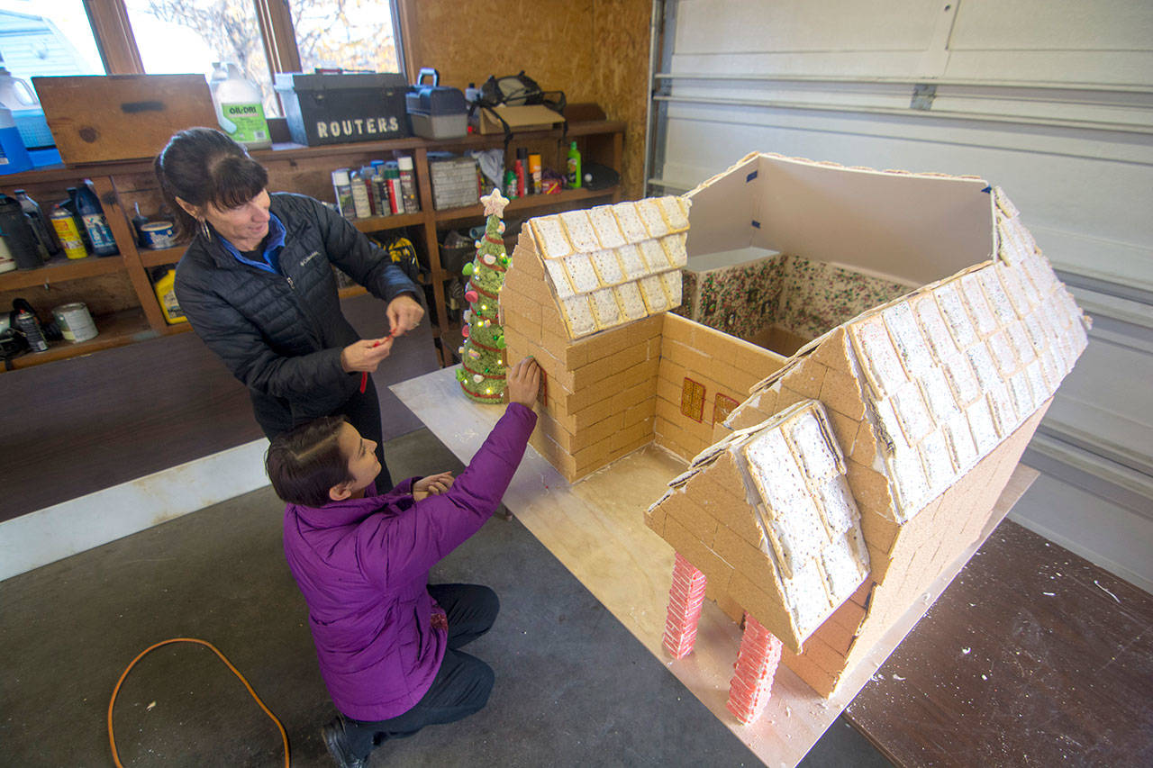 Renee Ochs, back, and Marie Finta work on a gingerbread house for this year’s Festival of Trees. (Jesse Major/Peninsula Daily News)