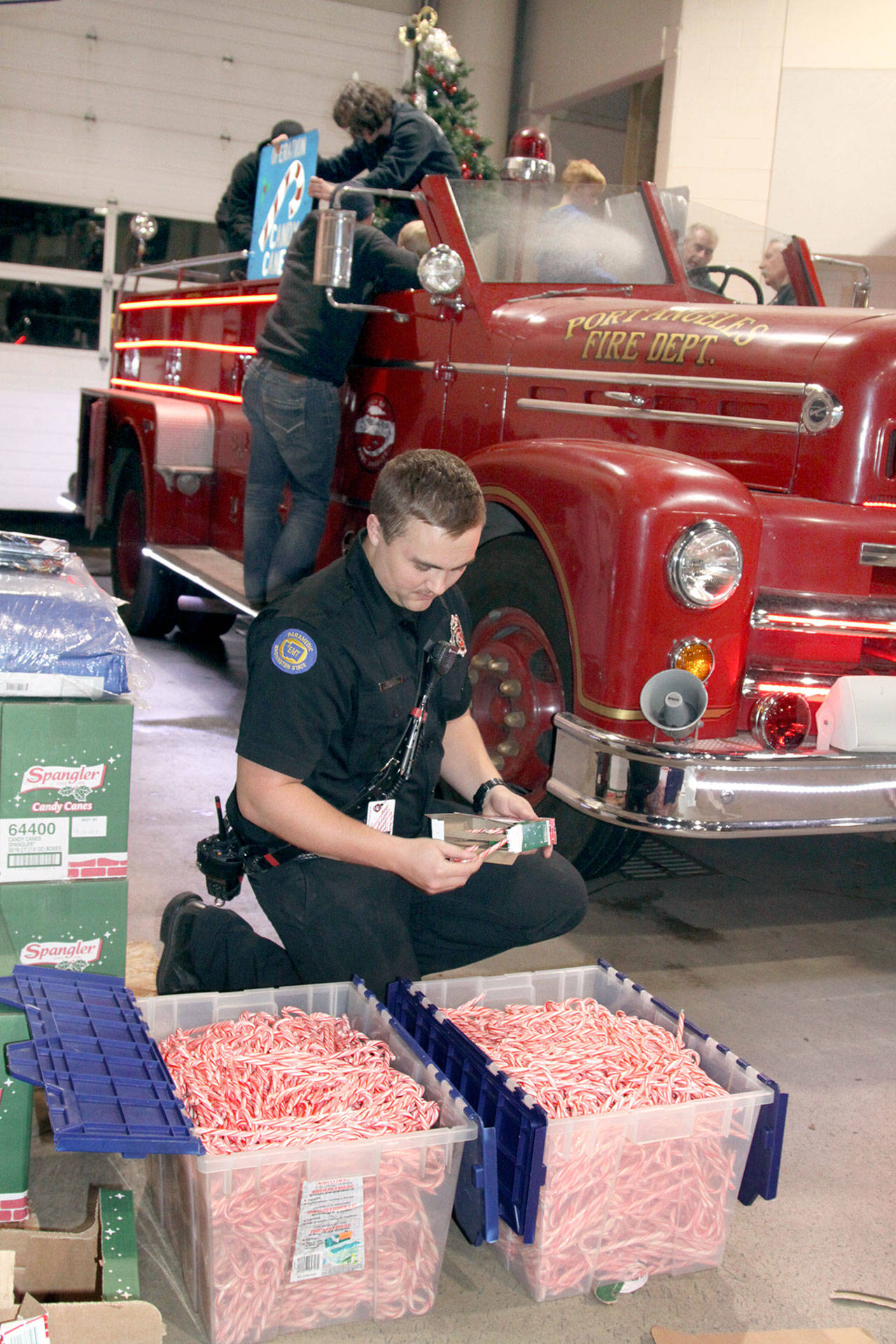 Firefighter/paramedic Tyler Gage fills up tubs with candy canes for the upcoming 34th annual Operation Candy Cane. Port Angeles firefighters and volunteers will be out in the evening starting Saturday to collect dry goods or cash for local food banks. Several thousand candy canes will also be handed out. (Dave Logan/for Peninsula Daily News)