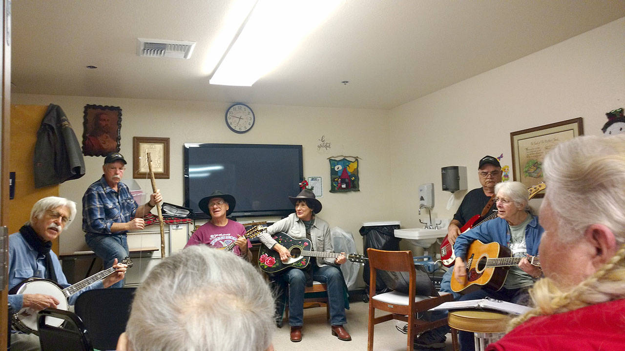 Barney Munger on banjo, Larry Baysinger on washtub bass, Dave Secord on mandolin, Rosalie Secord on guitar, Dave Lenahan on electic bass and Mary Munger on guitar are musicians from different bands who come together to jam for an audience at long term care within the Forks Community Hospital. (Zorina Barker/for Peninsula Daily News)