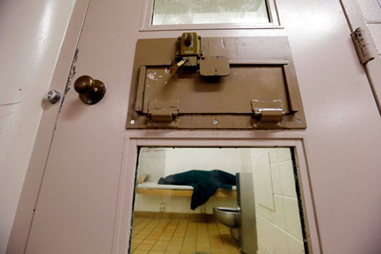 In this Oct. 15, 2014, file photo, an inmate huddles under a heavy blanket on a bunk in the psychiatric unit of the Pierce County Jail in Tacoma. (The Associated Press)