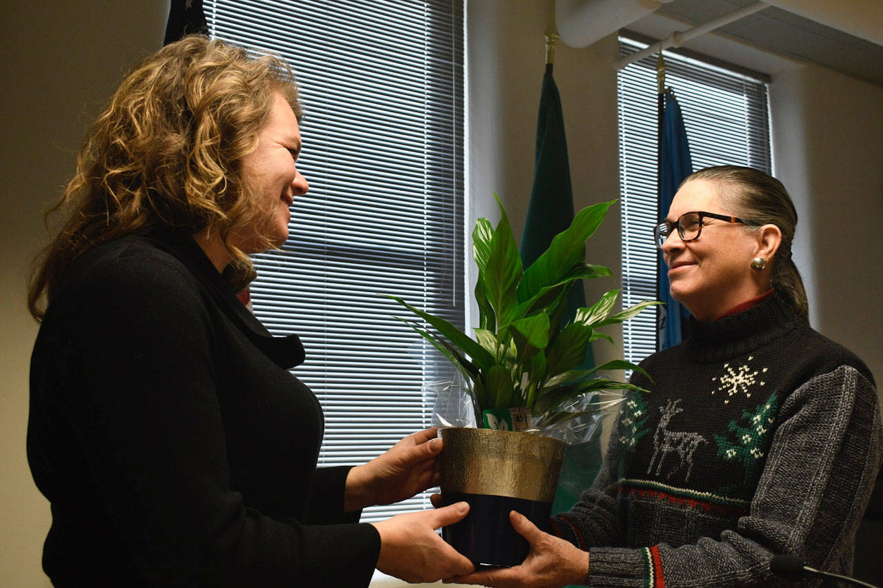 Jefferson County Commissioner Kate Dean, left, presents outgoing Commissioner Kathleen Kler with a peace plant at Monday’s meeting and thanked her for her four years of service. (Jeannie McMacken/Peninsula Daily News)