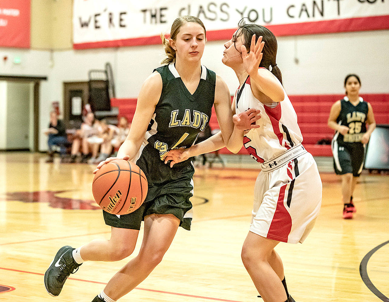 Steve Mullensky/for Peninsula Daily News Clallam Bay’s Miriam Wonderly drives around Redhawk Rosalyn Salmon and goes for the basket during a game in Port Townsend Monday night.