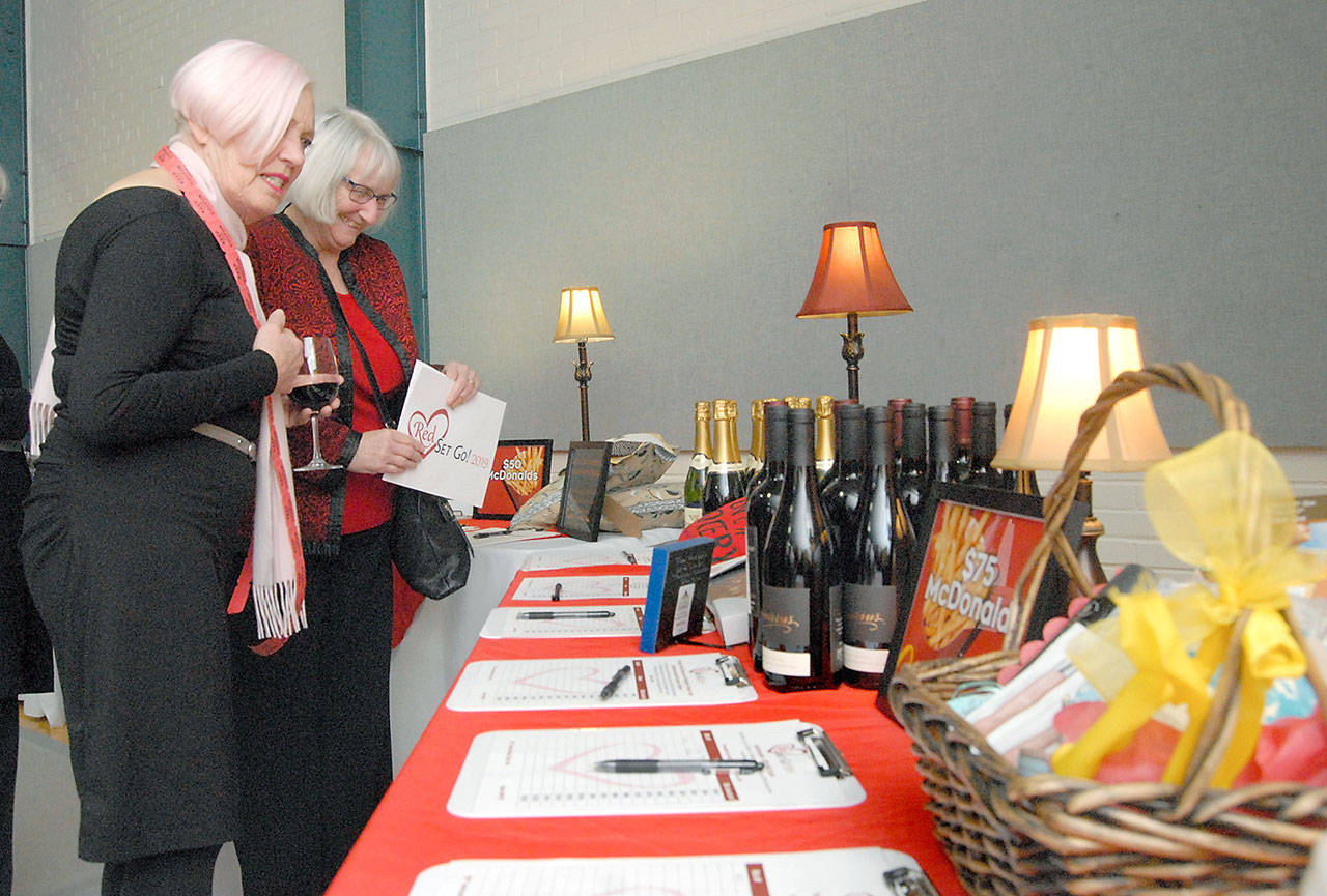 Alexis Sorensen, left, and Cindy Sofie, both of Port Angeles, examine a table of auction items during Friday’s 12th annual Red, Set, Go luncheon at Vern Burton Communty Center in Port Angeles. The event, designed to raise awarness of heart health for women, was a fundraiser for the Olympic Medical Center’s Heart Center. (Keith Thorpe/Peninsula Daily News)