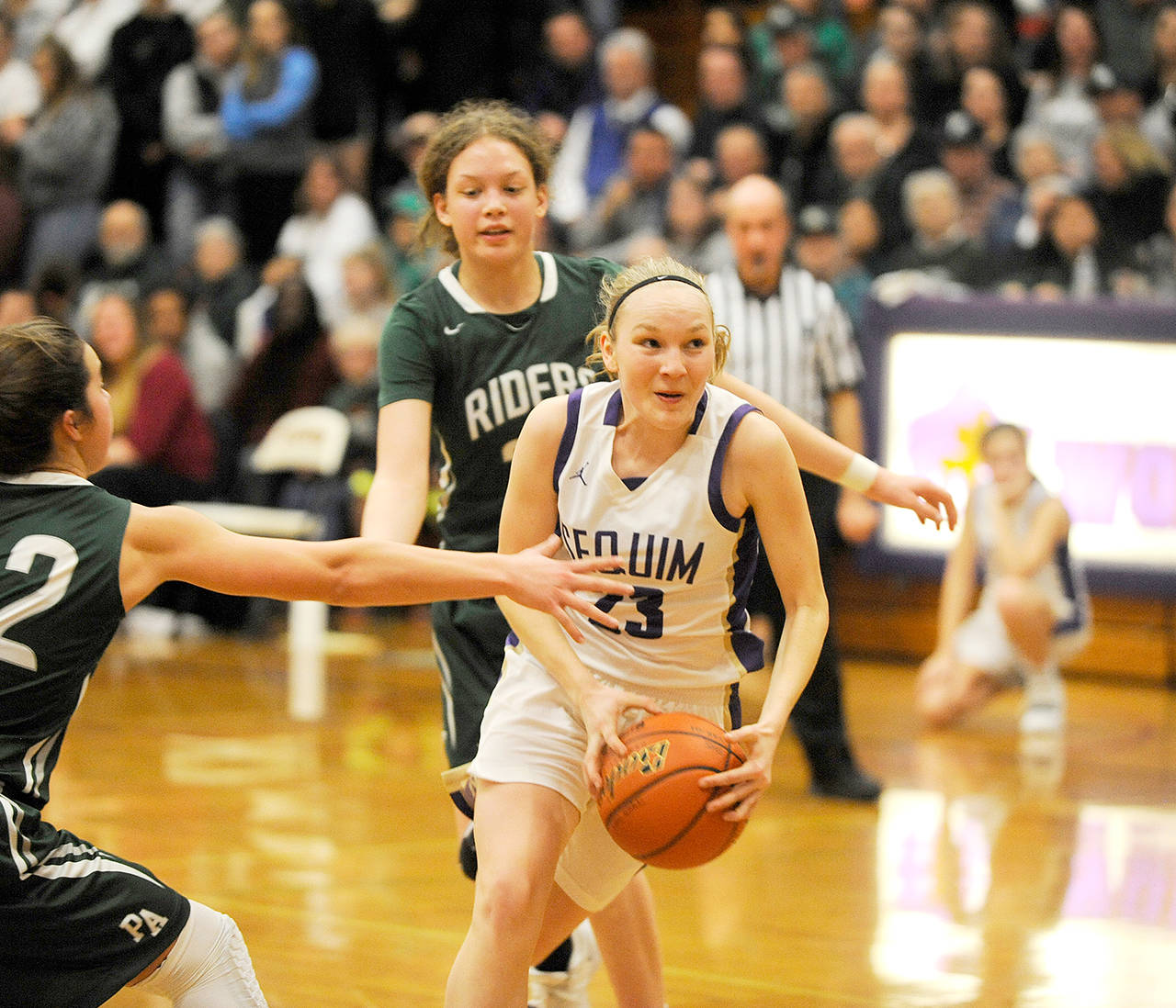 Michael Dashiell/Olympic Peninsula News Group Sequim’s Melissa Porter, center, splits the defense of Port Angeles’ Madison Cooke, back, and Eve Burke, left, during a Jan. 31 game in Sequim. The Wolves and the Riders meet for the third time this season today in a loser-out contest at the Class 2A state tournament at the Yakima SunDome.