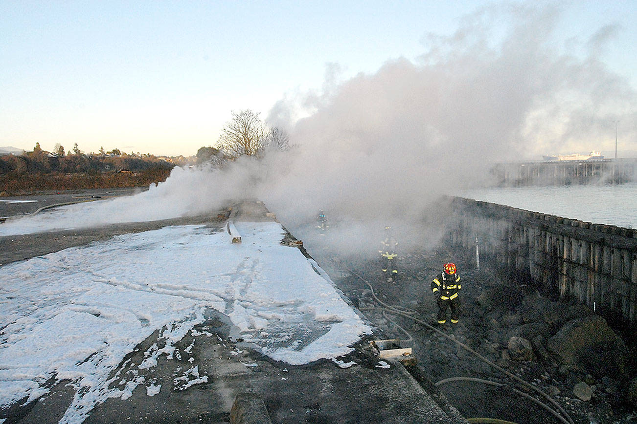 Port Angeles firefighters, with the assistance from Clallam County Fire District 2, work at the scene of a fire in pilings on Tuesday at the Rayonier pulp mill site east of downtown Port Angeles. (Keith Thorpe/Peninsula Daily News)