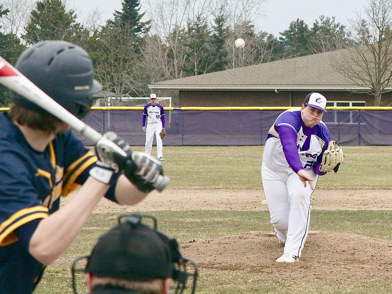 Sequim’s starting pitcher Caleb Pozernick fires a pitch to a Forks batter as the first game for both teams was played Monday at the Sequim field on a cold day with temperatures just 10 degrees above freezing.