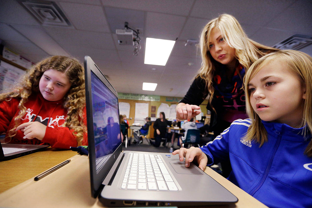 Computer science teacher Sheena York, center, helps fifth-grade students work on programming during their weekly computer science lesson at Marshall Elementary School in Marysville. (The Associated Press)