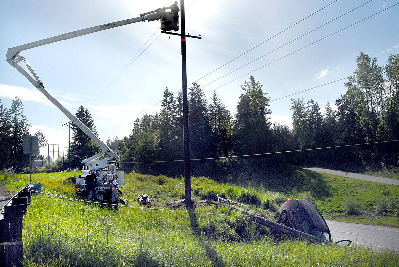 A Clallam County PUD crew repairs power lines on Wednesday morning after a car failed to negotiate a turn at the top of the Tumwater Truck Route early Wednesday morning and toppled a power pole. (Keith Thorpe/Peninsula Daily News)