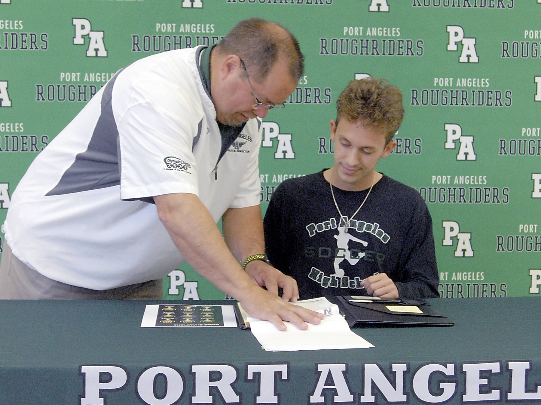 <strong>Keith Thorpe</strong>/Peinsula Daily News                                Port Angeles High School athletic director Dwayne Johnson, left, goes over paperwork on Wednesday with Andrew St. George as the senior signs a letter of intent to attend Peninsula College.